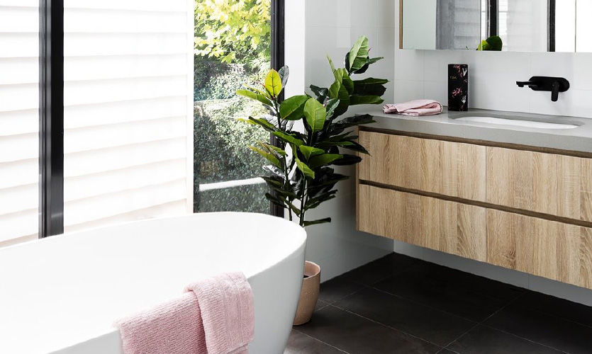 freestanding bath with a pink towel thrown over in a bright bathroom